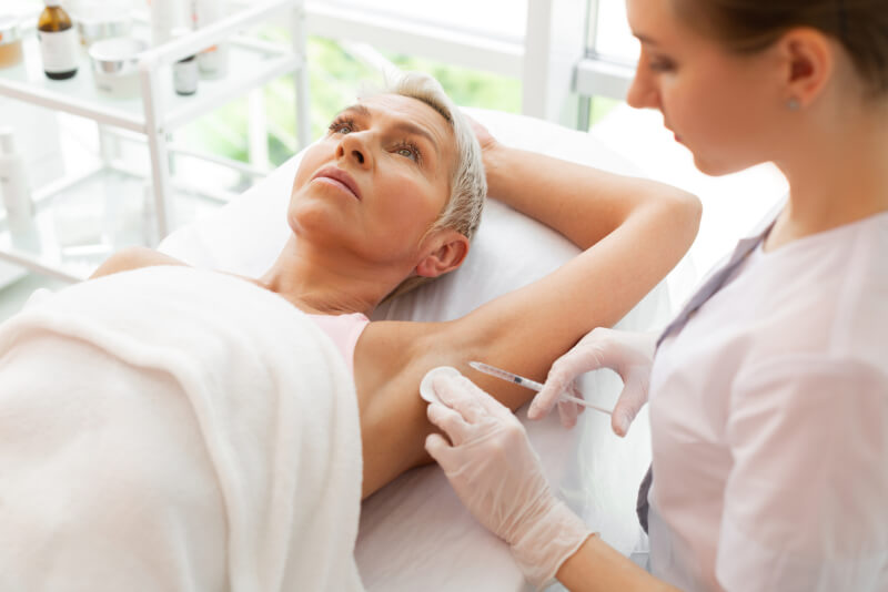 Botox is injected under the arms of clients by a botox injector