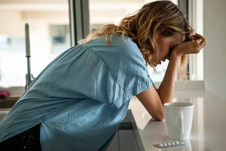Woman leaning on counter suffering from menstrual migraine