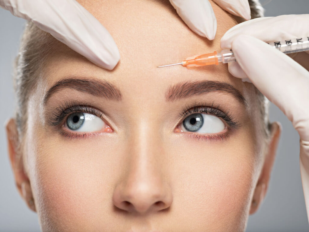 Caucasian woman getting cosmetic injection of botox in forehead