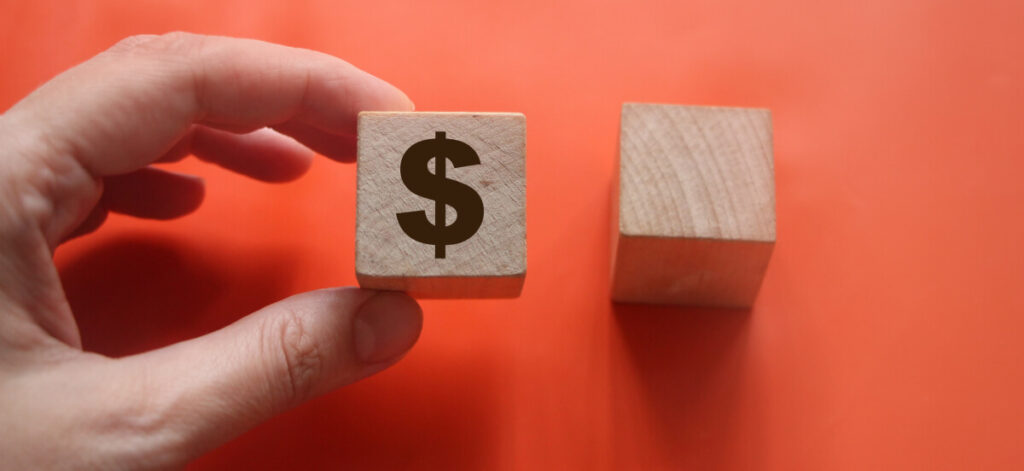 Wooden block with the US Dollar symbol in hand holding it and another empty one