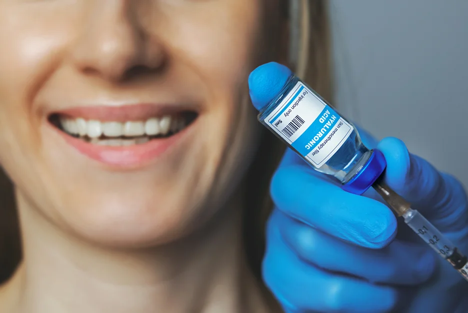 smiling woman while injector prepares filler injection